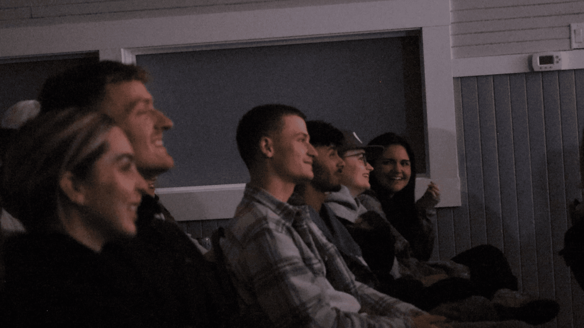 A row of people laughing in the dark.